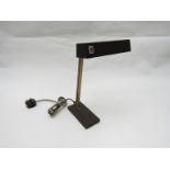 A painted metal desk lamp with adjustable brass arms