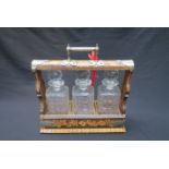 A pokerwork tantalus, three decanters and stoppers, nickel plated mounts,