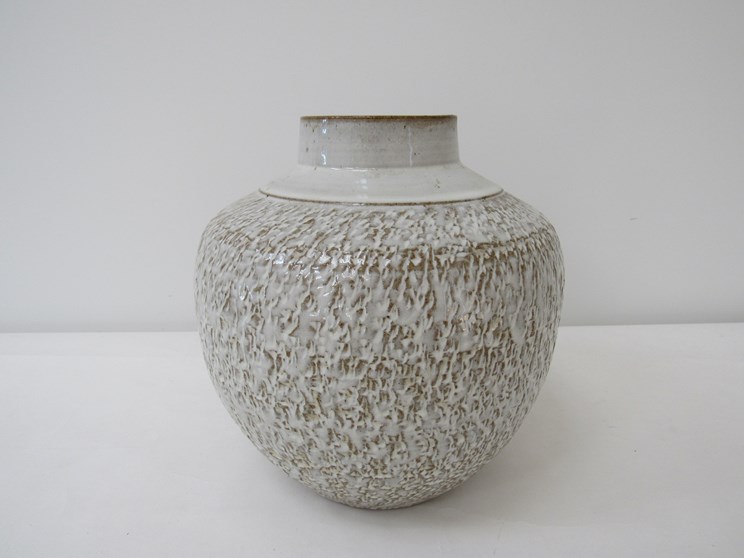 A large studio pottery stoneware vase with cream glaze over a textured body.