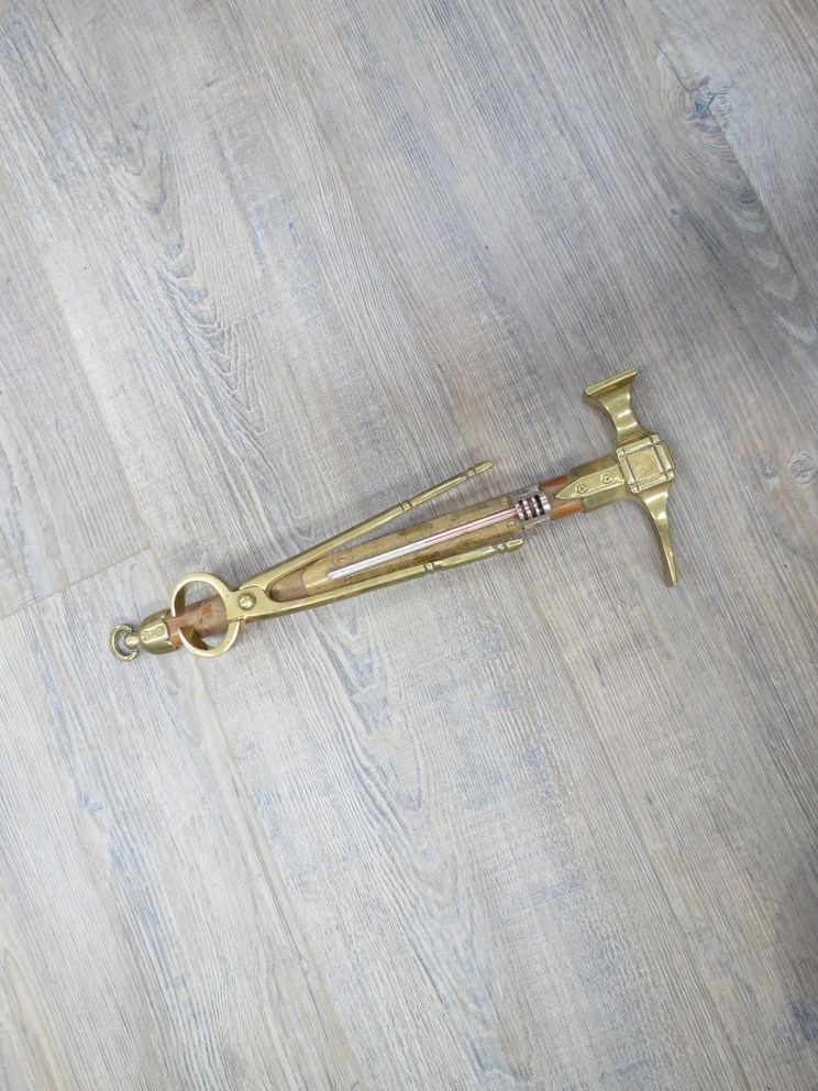 A brass hammer and pincers design wall hanging thermometer