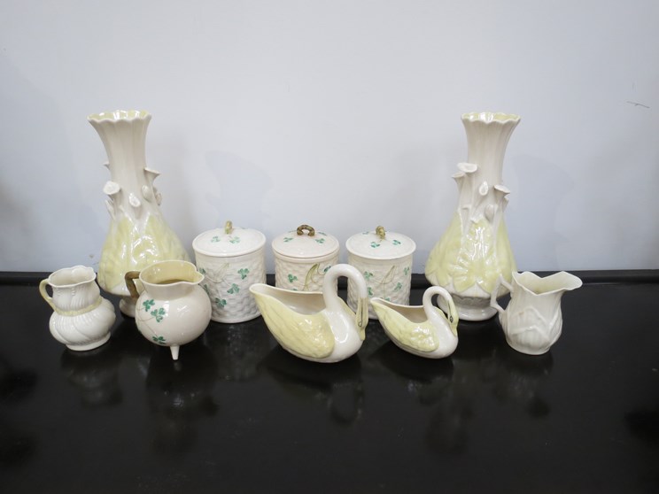 An assortment of Belleek items including a pair of vases, lidded containers and jugs etc.