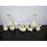 An assortment of Belleek items including a pair of vases, lidded containers and jugs etc.