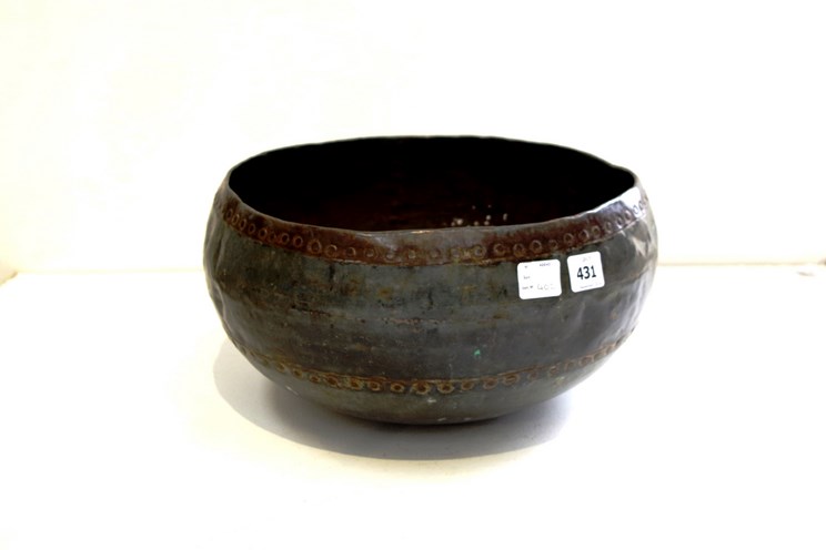 A late 19th Century Eastern hammered metal bowl of rivetted construction,