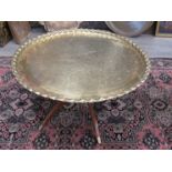 An Eastern brass coffee table with heavy beaded rim,