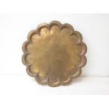 A late 19th Century colonial shaped brass tray with engraved pattern depicting regal figures,