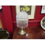 A bronzed base table lamp with mottled and tasseled shade