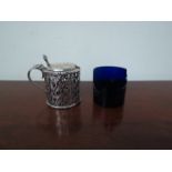 An HC Freeman & Co silver mustard, pierced scroll body with shell shaped thumb and blue glass liner,