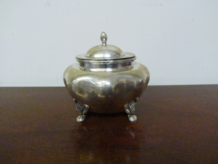 A miniature silver tea caddy of melon form raised on paw feet,