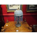 A bronzed base table lamp with blue mottled and tasseled shade
