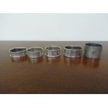 Five various napkin rings including engine- turned design,