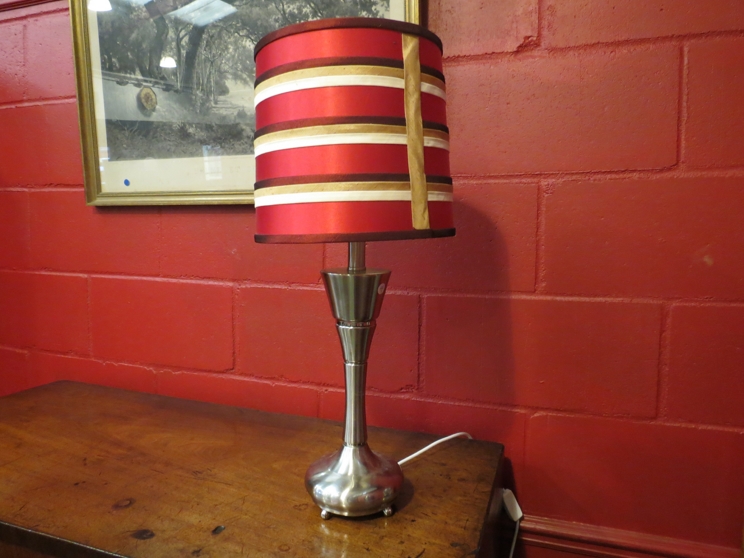 A modern chrome lamp with tapering stem,