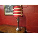 A modern chrome lamp with tapering stem,