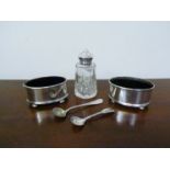 Two silver oval salts with two spoons and a silver topped pepperette,