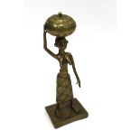 A Nigerian Fon brass figure of a standing woman carrying a basket on her head,