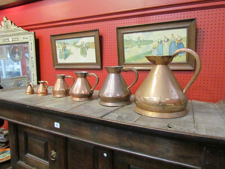 A set of six graduating copper measuring jugs