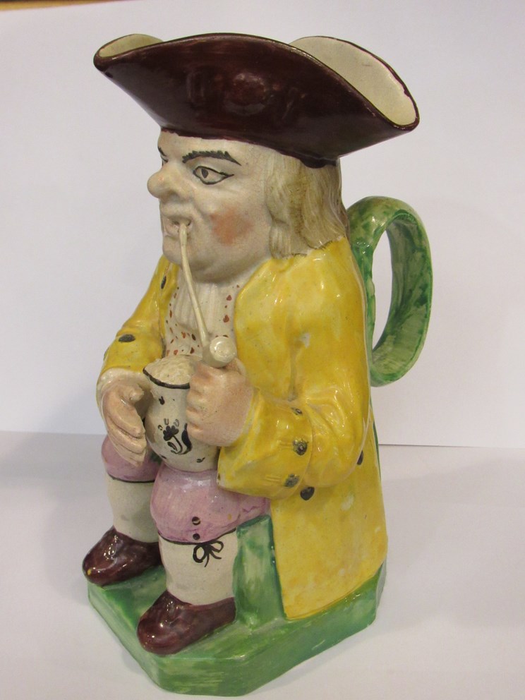 A late 18th / early 19th Century Staffordshire Toby jug, yellow jacket, smoking a pipe,