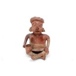 A tribal terracotta coloured clay figure of a seated woman holding a bowl,