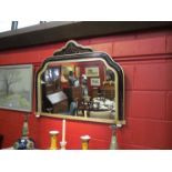 An overmantel mirror with ebonised frame painted with a gilt crest