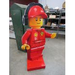 A Lego man advertising board dressed in Ferrari pit overalls,