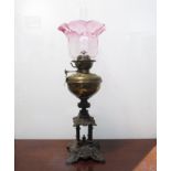 A Victorian Veritas oil lamp with cranberry shade, brass reservoir,