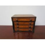 A 19th Century miniature chest of four drawers with pillar detail and quarter veneered