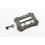 An ornate silver buckle, embossed foliate decoration,