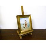 A 19th Century gilt framed oil on ceramic plaque depicting lady in dress with cherub standing at