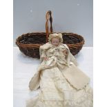 A Victorian/ Edwardian bisque head, closed mouth baby doll, no markings, in a basket,