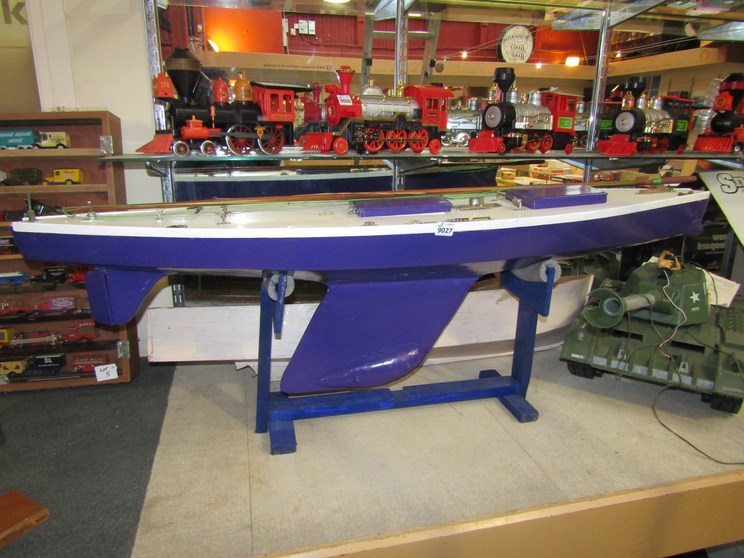 A wooden model pond yacht on stand together with a wooden launch hull