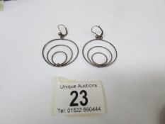 A pair of unusual pendant earrings fashioned as circles in silver,