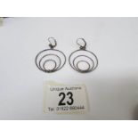 A pair of unusual pendant earrings fashioned as circles in silver,