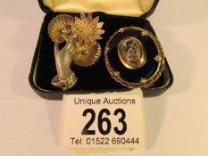 A Victorian mourning brooch with hair locket and a brooch of a hand holding 2 sea shells,