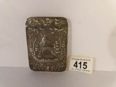 An unmarked white metal card case depicting a castle and a church dated 1853, 9 x 6.