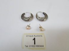 A pair of silver hoop earrings and a pair of silver stud earrings