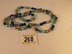 A long necklace of multi coloured cultured pearls