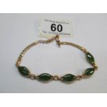 A yellow metal and jade bracelet