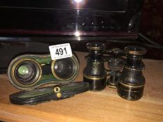 A small pair of field binoculars with compass and a cased pair of binoculars