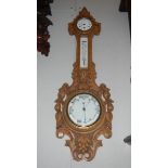 An Edwardian oak aneroid barometer with clock & porcelain faces,