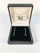 A pair of gold earrings set green and white stones