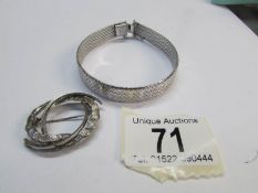 A silver bracelet and a white metal brooch