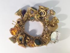 A 9ct gold charm bracelet with 31 charms and fobs, 14 marked 9ct (325) and 17 unmarked yellow metal,