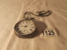 A silver pocket watch in working order with key and silver watch chain,