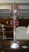 A silver plated Corinthian column oil lamp with cranberry glass font and shade