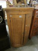 A pine bow front hanging corner cupboard with 3 shelves, height 107 cm,