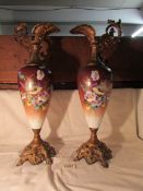 A pair of Victorian ceramic bodied ewers with metal bases and tops hand painted with bird scenes