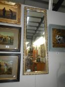 A tall gilt framed bevel edged mirror