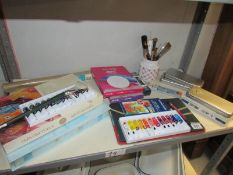 A shelf of art materials including paints,