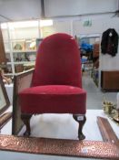 A Victorian nursing chair on pad feet and with splayed back legs