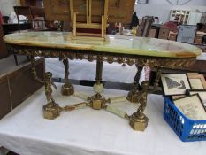 A brass coffee table with marble top supported by cherubs