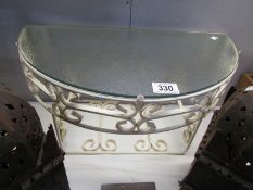 A wrought iron and glass wall shelf